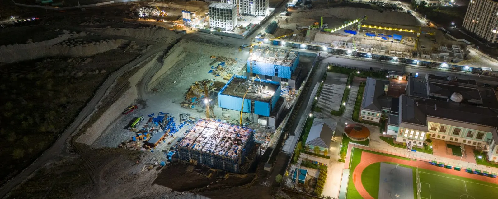 Verlichte bouwplaats bij nacht, gezien vanuit de lucht