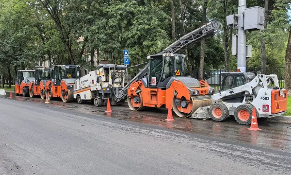 Asfalteermachines en shovels op een rij langs een weg in aanleg